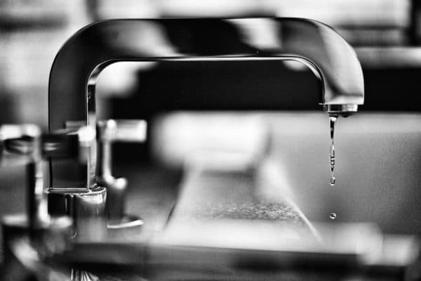 Photo en noir et blanc d'un robinet qui fuit.