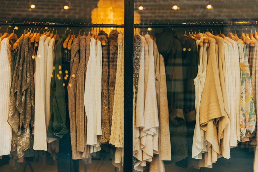 vêtements sur portants derrière une vitre.