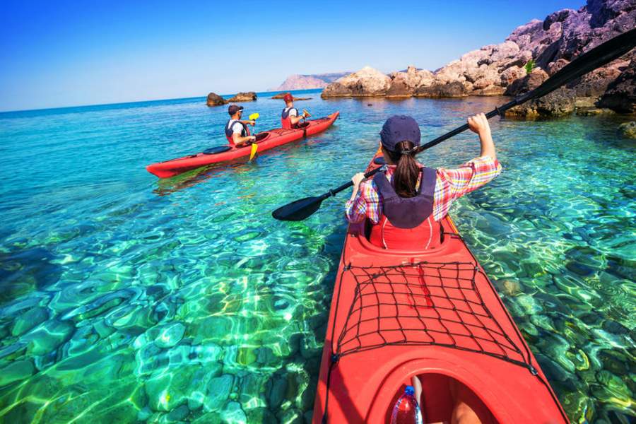 femme en canoe kayak au premier plan et deux hommes en canoë kayak au second plan