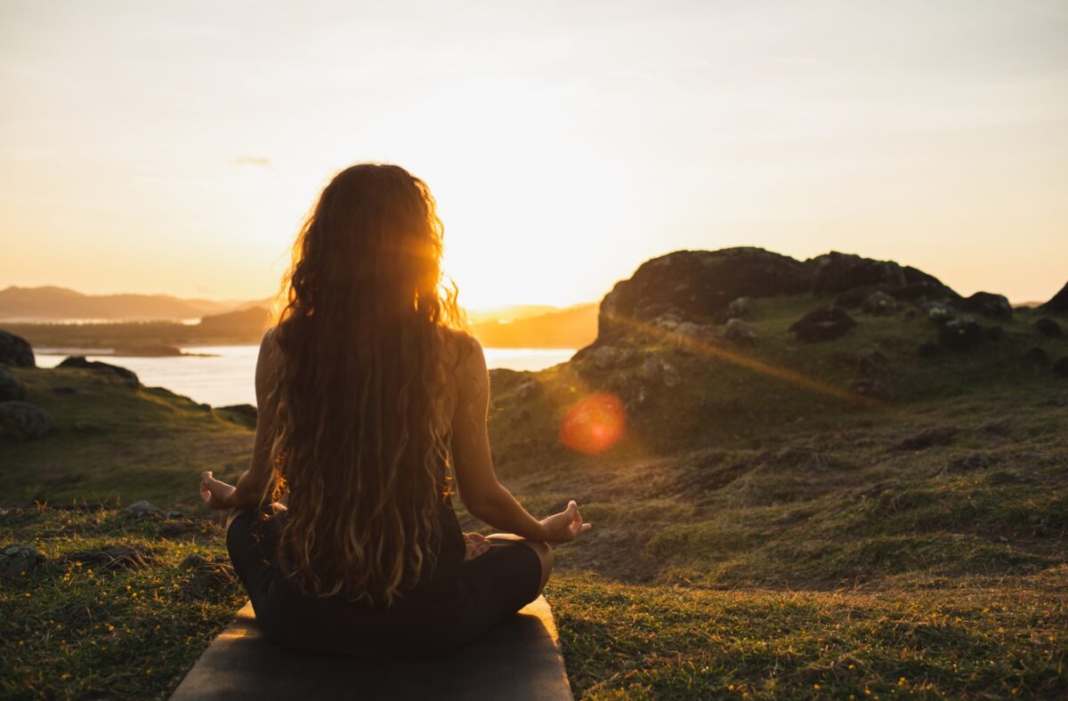 Femme en position de yoga devant un lever de soleil