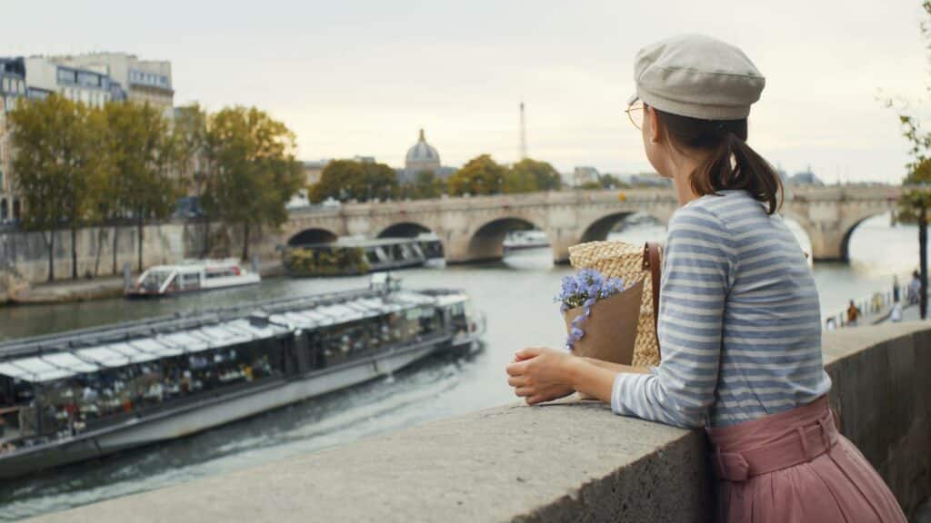 jeune fille regardant une péniche passer sur la Seine à Paris