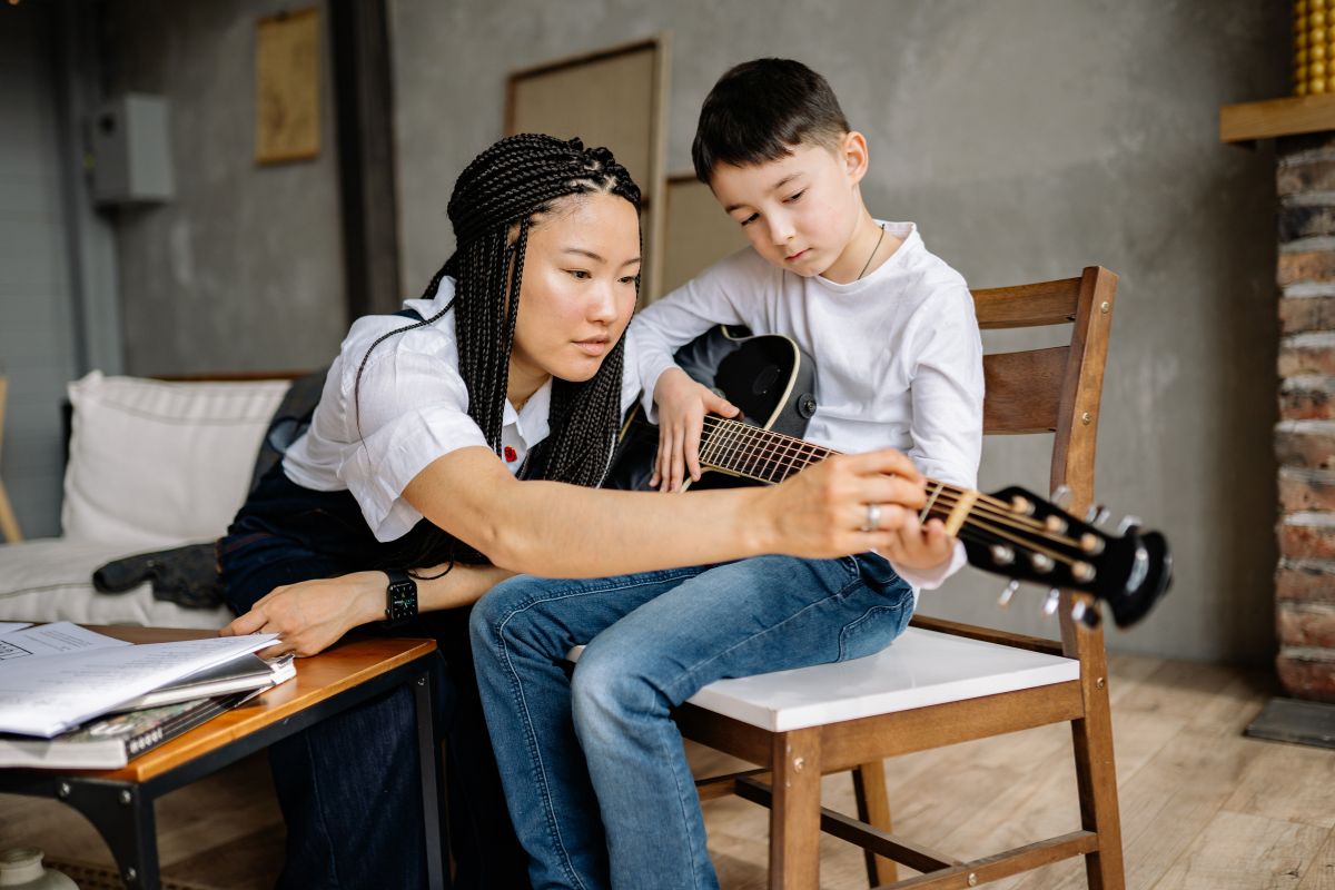 Un jeune garçon apprend à jouer la guitare. 