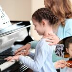 Une petite fille apprend à jouer au piano après l'apprentissage du violon