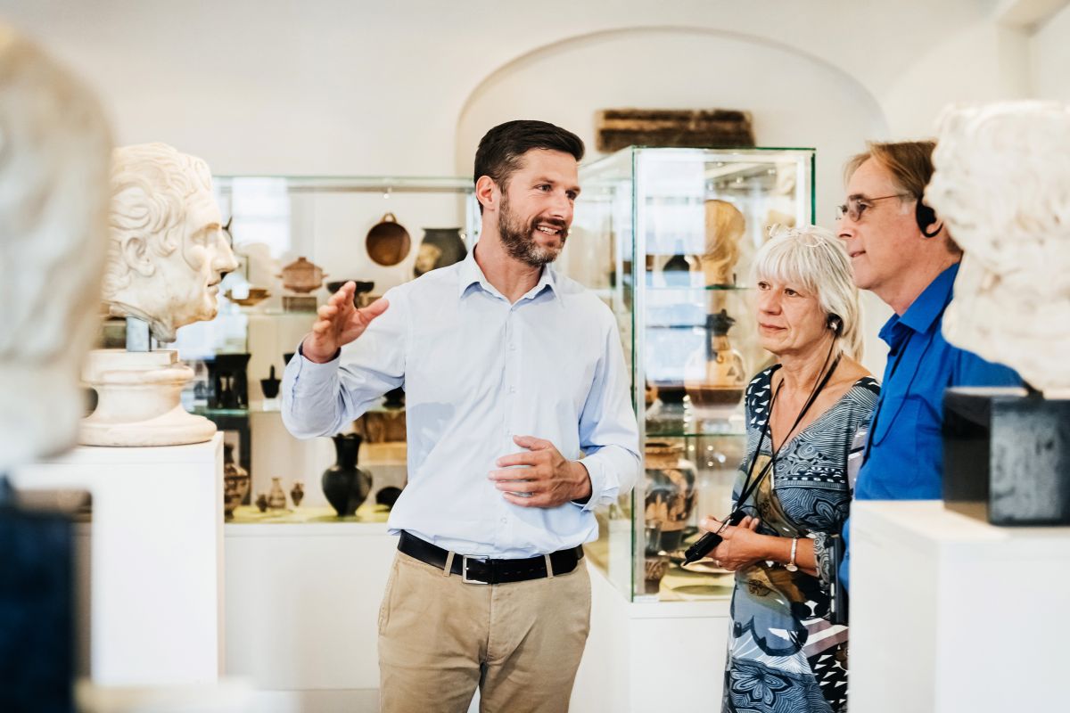 Un guide présente des œuvres artistiques à un couple en visite de musées. 